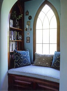 a window seat in front of a book shelf filled with books