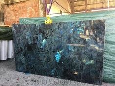 a large black marble slab sitting on top of a cement floor next to a green tarp