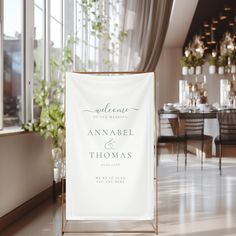 a wedding sign sitting on top of a white floor next to a window with lots of greenery