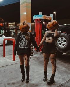 two women in costumes walking down the street with pumpkins on their heads and legs