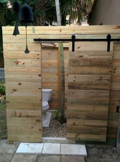 an outdoor toilet area with two doors open