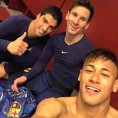 three young men posing for a photo in the locker room with one pointing at the camera