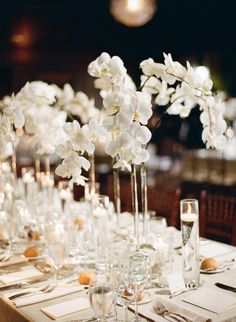 the table is set with white orchids and place settings for guests to sit at