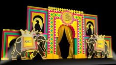 an elaborately decorated stage with two elephants and a man on one side, in front of a black background