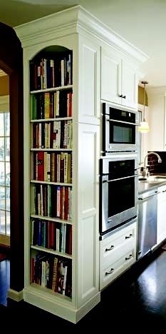 a kitchen with an oven, microwave and bookcase