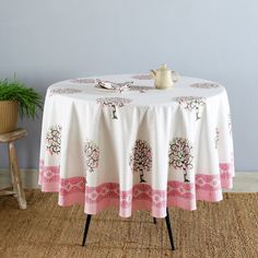 a table with a white and pink tablecloth on it next to a potted plant