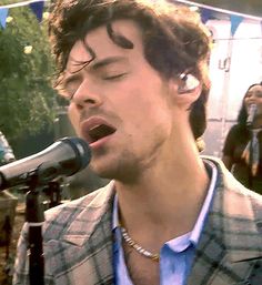 a man singing into a microphone while standing in front of a group of other people