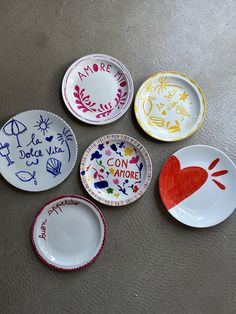 four plates with different designs on them sitting on a table next to each other and one has a heart painted on it