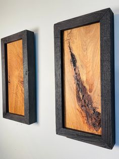 two wooden framed pictures hanging on the wall next to each other, one with a piece of wood in it's middle