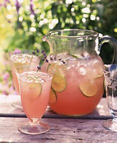 pitcher and glasses filled with lemonade sitting on a wooden table next to two pitchers