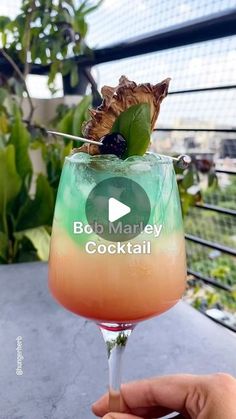 someone holding up a glass with a drink in it and the words bob marley cocktail