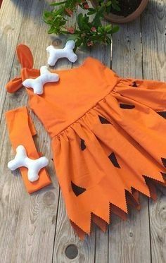 a dress made out of orange fabric with white bones on it and two bone clips