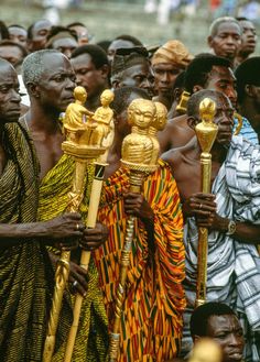 a group of people standing next to each other holding gold objects in their hands and looking at the camera