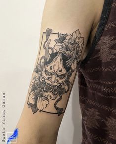 a woman's arm with a tattoo on it that has an image of a demon and flowers