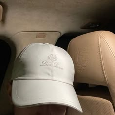 a man wearing a white hat sitting in the back seat of a car with his head up