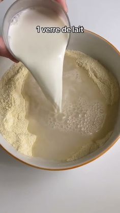 a person pouring milk into a bowl filled with flour