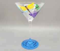 a wine glass with a dragonfly painted on the side and a blue base is shown