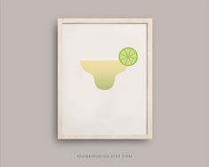 a framed poster with a lime slice in the shape of a cocktail glass on a gray background