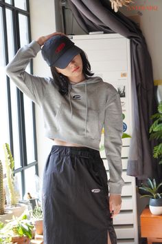 a woman wearing a grey sweatshirt and black skirt