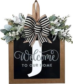 welcome to our home sign with bow and greenery on the front door hanger