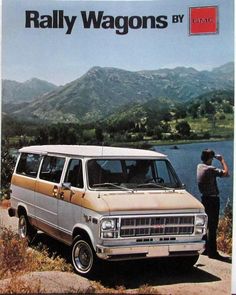 an old van parked next to a lake with mountains in the background and a man taking a photo