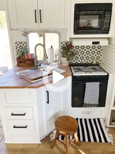 a small kitchen with white cabinets and wood counter tops, black and white patterned backsplash