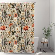 a shower curtain with flowers and plants on it in a white bathtub next to a potted plant