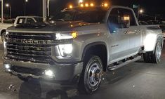 a silver truck is parked in a parking lot at night with lights on it's headlamps