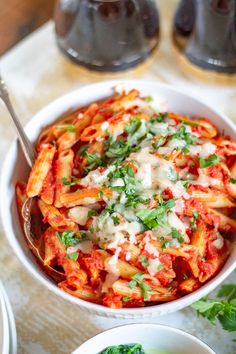 two bowls filled with pasta and sauce on top of a table