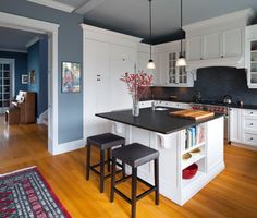 a kitchen with an island and stools in the center, along with blue walls