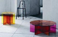 three colorful tables sitting on top of a white floor next to each other in an empty room