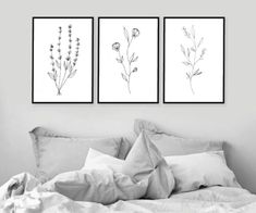 three black and white flowers are hanging on the wall above a bed in a bedroom