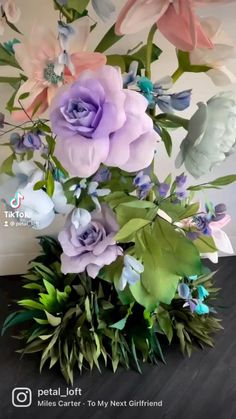 a vase filled with lots of flowers on top of a table