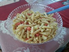 a bowl filled with pasta and vegetables on top of a lace tablecloth covered table