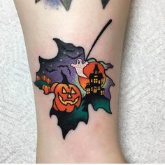 a halloween themed tattoo on the leg of a person with a bat and pumpkins