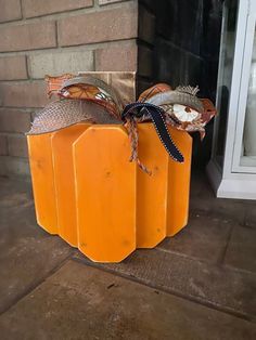 two orange pumpkins sitting on the ground next to a brick fireplace with ribbons tied around them