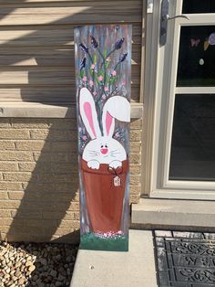 a painting of a bunny sitting in a flower pot on the side of a house