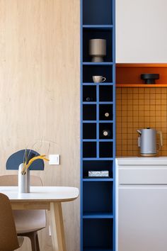 a kitchen with blue shelves next to a white table