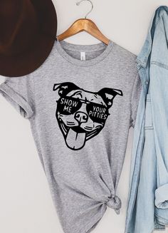 a t - shirt that says show me your dogs on it next to a hat and jeans