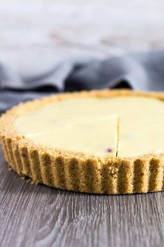 a cheesecake on a wooden table with a blue napkin in the background and one slice missing