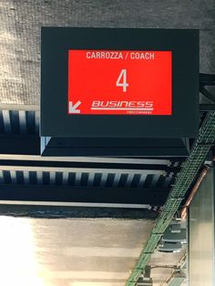 a red sign hanging from the side of a metal staircase in an office building that says garroza / coach 4 business