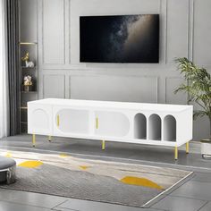 a white entertainment center with yellow accents in a living room setting, next to a large painting on the wall