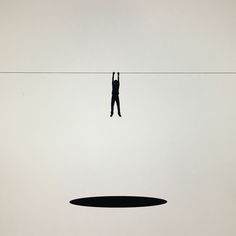 a person standing on a wire with their arms in the air and holding onto an object