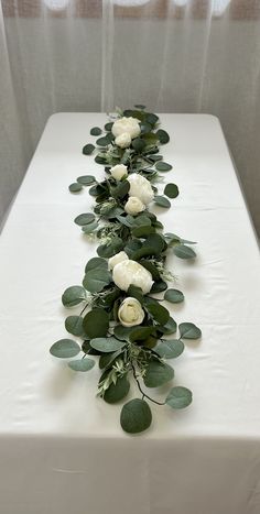 a long table with white flowers and greenery on it