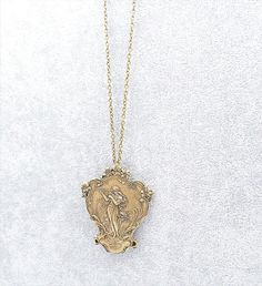 This stunning Art Nouveau style necklace featured a larger over sized stamped metal brass pendant depicting a romantic soft image of a Maiden Goddess playing a Musical harp. The pendant also features many flowers and a dragonfly on the bottom. The pendant is hollow on the back so it is very light weight - please view all pictures to see the back. The pendant is large and measures 2 1/2 inches long by 2 inches wide. I have suspended this pendant from a brass cable chain complete with a lobster cl Vintage Coin Pendant Necklace For Wedding, Antique Gold Brass Necklace For Wedding, Vintage Wedding Necklace With Coin Pendant, Vintage Wedding Coin Pendant Necklace, Antique Gold Necklace With Antique Finish For Wedding, Antique Gold Wedding Necklace With Antique Finish, Vintage Bronze Necklaces With Coin Pendant, Vintage Bronze Necklace With Coin Pendant, Antique Gold Medallion Necklace For Vintage Collection