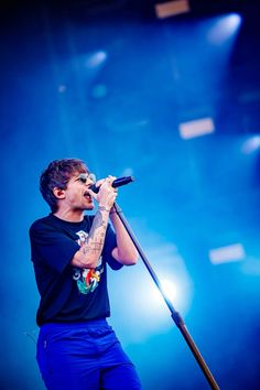 a man standing on top of a stage holding a microphone in his hand and singing