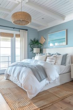 Coastal-themed bedroom with a wicker light fixture, light blue walls, a bed with white and gray bedding, and a large window with ocean views. Country Cottage Living, Coastal Bedroom Decorating, Summer Bedroom, Coastal Room, Feminine Bedroom, Casa Country, Casa Vintage, Coastal Bedrooms, Beach Bedroom