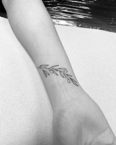 a black and white photo of a woman's arm with a tattoo on it