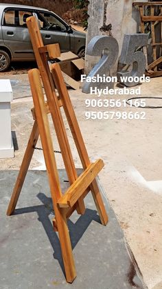 a wooden easel sitting on top of a cement slab in front of a car