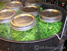 jars filled with green beans sitting on top of a stove